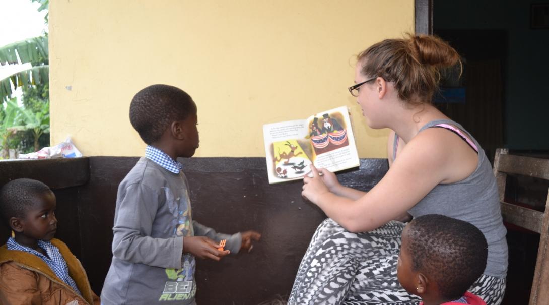 Local children listen to a global gap year volunteer reading aloud at a daycare centre in Akuapem Hills, Ghana. A volunteer reads aloud to children in Ghana during her global gap year abroad.